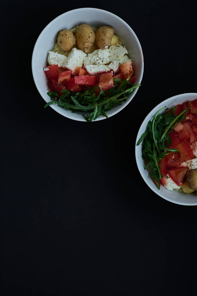 Fondo negro y tazones con saludable, útil kus-kus desayuno con verduras, tomates, champiñones, rúcula y queso
. - Foto, Imagen