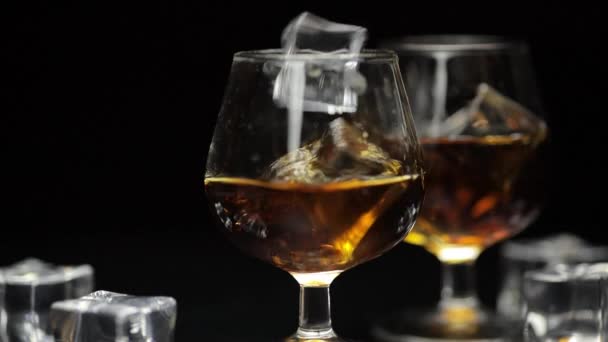 Jääkuutioita tippui lasilliseen alkoholia juoda viskiä, konjakkia. Hidastus
 - Materiaali, video