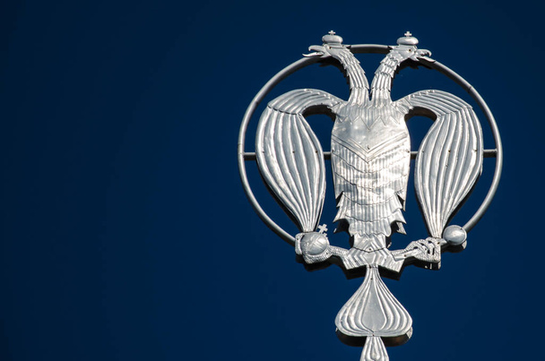 Coat of arms of Russia, silver double-headed eagle against the background of blue sky. Silver Russian heraldic symbol, background with copy space. - Fotoğraf, Görsel