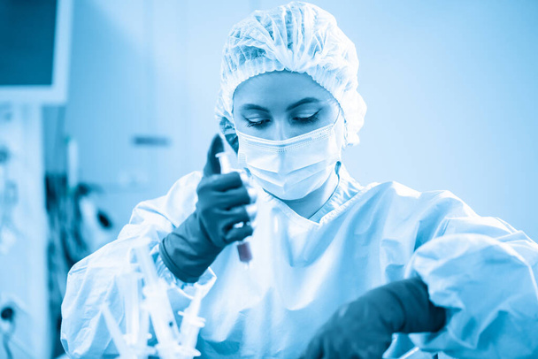 Женщина-химик-эпидемиолог в защитных перчатках проводит тесты со шприцем в лаборатории. Создание вакцины против вируса Kovid 19. Борьба с бактериями и
 - Фото, изображение