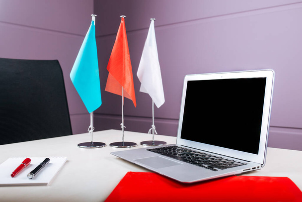 Office workplace with a laptop notebook pens flags - Photo, Image