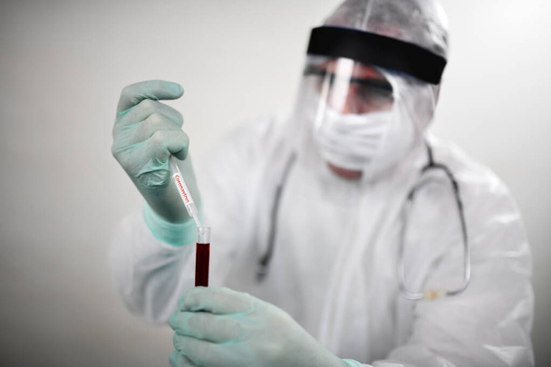 Il medico indossa una maschera respiratoria e tiene il campione di sangue di Coronavirus Covid-19. Test degli scienziati per il virus Covid-19 o Corona Utilizzando tubi scientifici per la ricerca e il trattamento di malattie in un laboratorio o ospedale. Concetti di trattamento medico
 - Foto, immagini