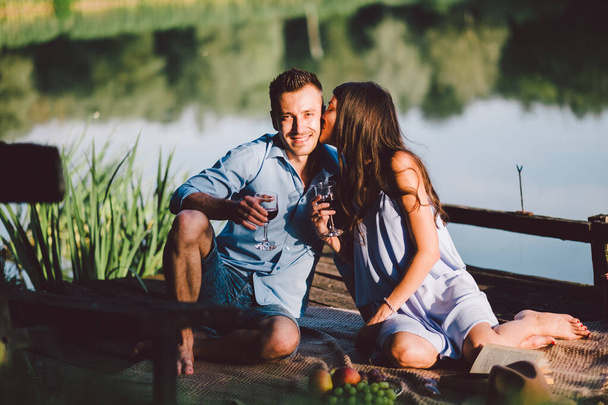 feliz jovem casal beber café enquanto sentado no banco perto do rio - Foto, Imagem
