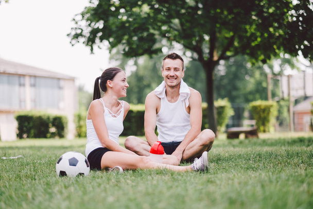 young couple sitting on the grass and having fun - Fotoğraf, Görsel
