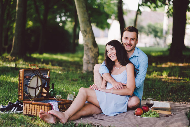 happy couple sitting on bench in garden with picnic - Φωτογραφία, εικόνα