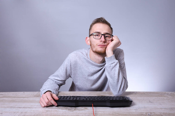 Zabawny kujon młody biznesmen, człowiek pracujący na komputerze.Wpisanie programisty klawiatury w okularach przed komputerem. - Zdjęcie, obraz
