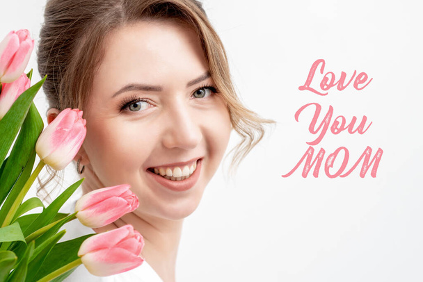 Love You Mom růžový text a krásná žena s růžovými tulipány na bílém pozadí. Koncept dne matek. - Fotografie, Obrázek