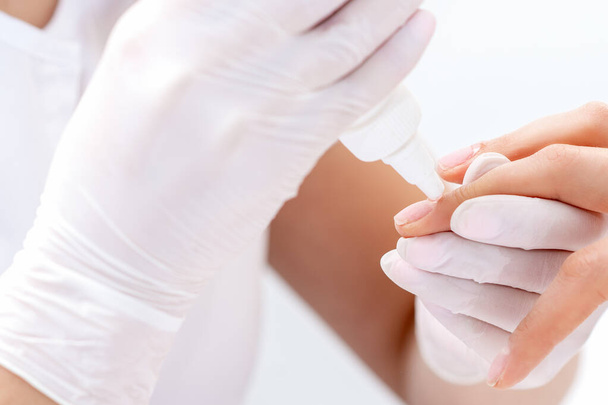 Le mani di specialista di manicure stanno applicando la colla per unghia di donna vicino. Manicurista utilizza strumento manicure
. - Foto, immagini