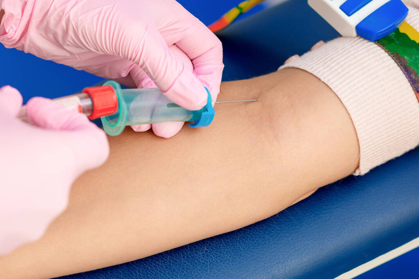 Nurse introducing the coronavirus vaccine introducing a needle into a vein of arm of woman. - Foto, Bild