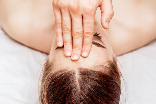 Top view woman receiving forehead massage by fingers of massage therapist. - Φωτογραφία, εικόνα