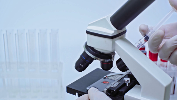 oříznutý pohled vědce, který zkoumá vakcínu na mikroskopu - Záběry, video