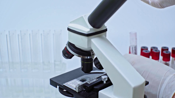 przycięty widok naukowca dodającego próbkę krwi koronawirusa do płynu - Materiał filmowy, wideo