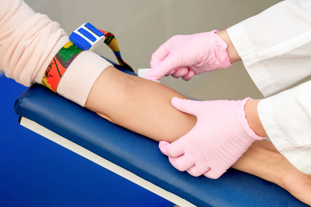 Τα χέρια νοσηλευτή απολυμαίνουν το δέρμα του βραχίονα πριν από τη χορήγηση του εμβολίου ένεσης στο ιατρικό κέντρο. - Φωτογραφία, εικόνα