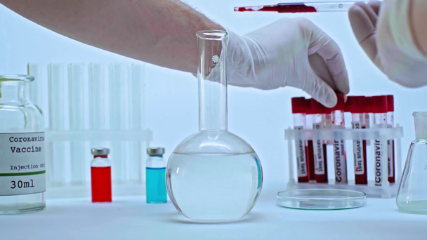 καλλιεργημένη άποψη του επιστήμονα που προσθέτει δείγμα αίματος κορωναϊού στο εμβόλιο σε φιάλη - Πλάνα, βίντεο
