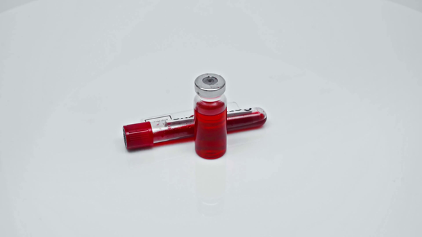 vzorek koronavirové krve ve zkumavce a laboratorním skle poblíž vakcíny - Záběry, video