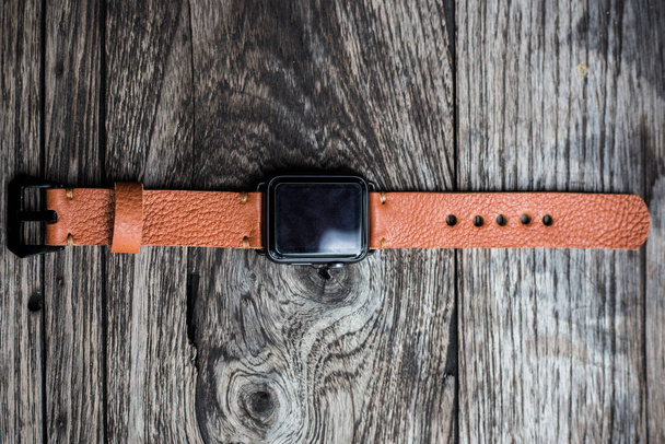 pulseira de relógio de couro marrom genuíno no fundo de madeira, artesanato objeto de trabalho - Foto, Imagem
