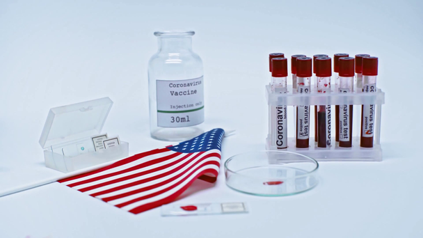 rack focus van de Amerikaanse vlag en coronavirus bloedmonsters en vaccin in het lab - Video