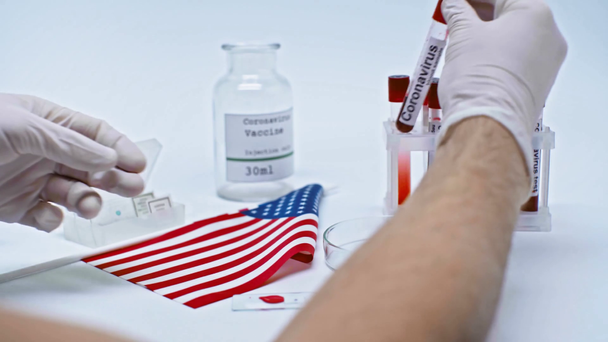Koronavirüs kan örneklerini Amerikan bayrağının yanında tutan bilim adamının görüntüsü. - Video, Çekim