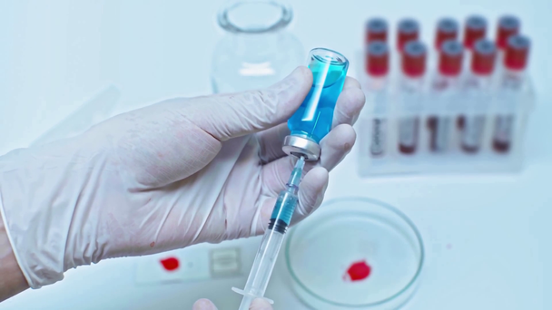 обрезанный вид ученого, принимающего голубую вакцину в шприце
 - Кадры, видео