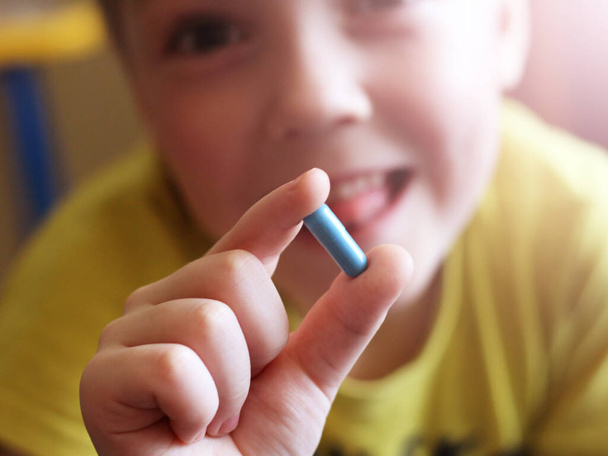 Çocuğun elinde mavi bir kapsül, makro, ilaç var. - Fotoğraf, Görsel