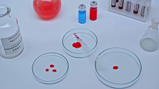laboratorní sklo s kapkami krve a koronavirovou vakcínou v lahvičkách - Záběry, video