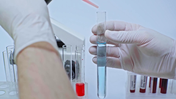 καλλιεργημένη άποψη του επιστήμονα προσθήκη κόκκινου υγρού στο μπλε στο εργαστήριο - Πλάνα, βίντεο