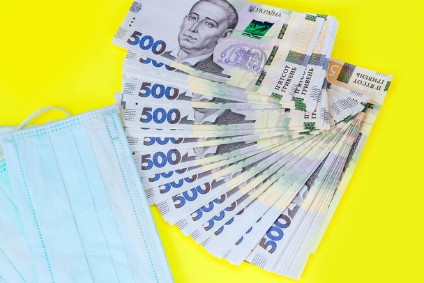 Hryvnia dinero ucraniano con máscara de protección médica, concepto
. - Foto, Imagen