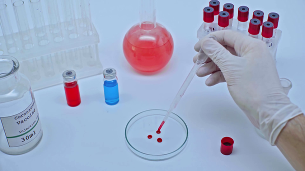 обрезанный вид ученого, добавляющего капли крови коронавируса на чашку Петри
 - Кадры, видео