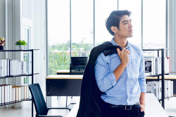 Giovane imprenditore asiatico è in piedi pose intelligenti e sorridere allo spazio di co-working decorato in stile ufficio moderno per gli studenti di business startup e freelance
 - Foto, immagini