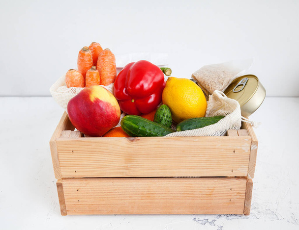 Donation wooden box with various food. Canned food, cereals, fruits, vegetables. White background. - Φωτογραφία, εικόνα