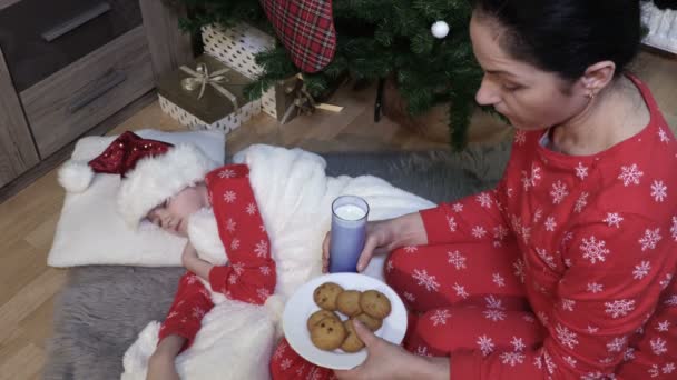 Noel arifesinde Noel Baba için pijamalı kadın süt ve kurabiye tutuyor. - Video, Çekim