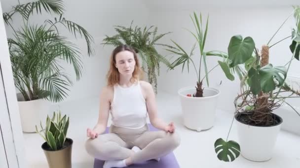 Mädchen in Sportbekleidung sitzt mit geschlossenen Augen in Lotus-Pose und genießt Meditation - Filmmaterial, Video
