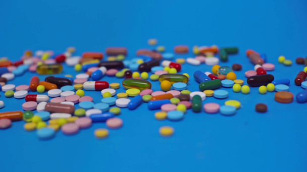 Selective focus of colorful pills on blue surface - Filmagem, Vídeo