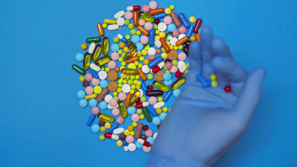 Top view of doctor putting pills on spinning blue background - Filmagem, Vídeo