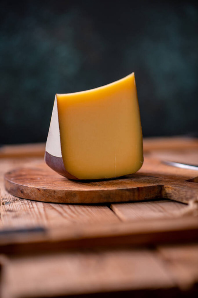 Hard cheese parmesan on wooden board on sunlight table traditional table texture side view - 写真・画像