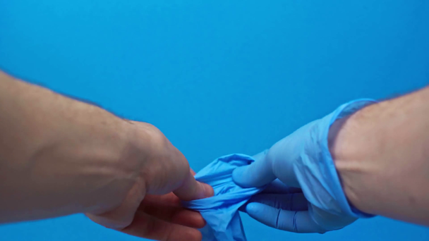 vista ritagliata dell'uomo che indossa guanti di lattice isolati sul blu, concetto covid-19
 - Filmati, video