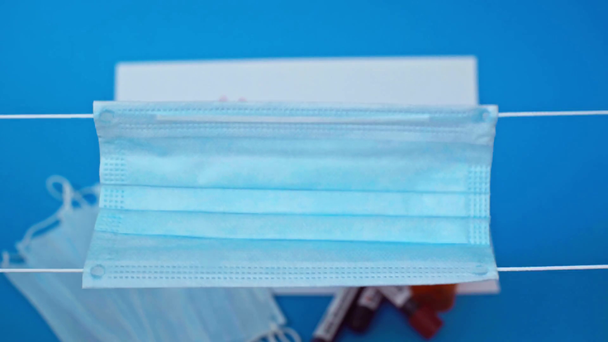 przycięty widok człowieka w lateksowych rękawiczkach pokazujących maskę medyczną odizolowaną na niebiesko - Materiał filmowy, wideo