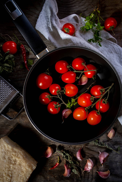 Cherry tomatoes freshly picked and thrown into the pan with various spices - Foto, imagen