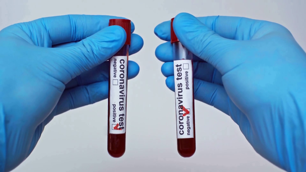 oříznutý pohled na lékaře zobrazující koronavirové zkumavky izolované na šedé - Záběry, video