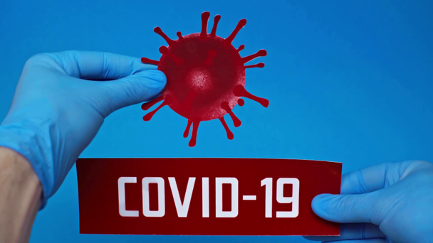 visão cortada do homem com bactérias coronavírus e cartão covid-19 isolado em azul
 - Filmagem, Vídeo