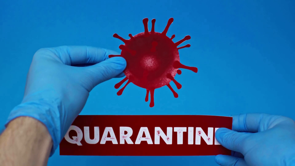 férfi kéz koronavírus baktériumokkal és karanténkártyával, kék alapon izolálva - Felvétel, videó