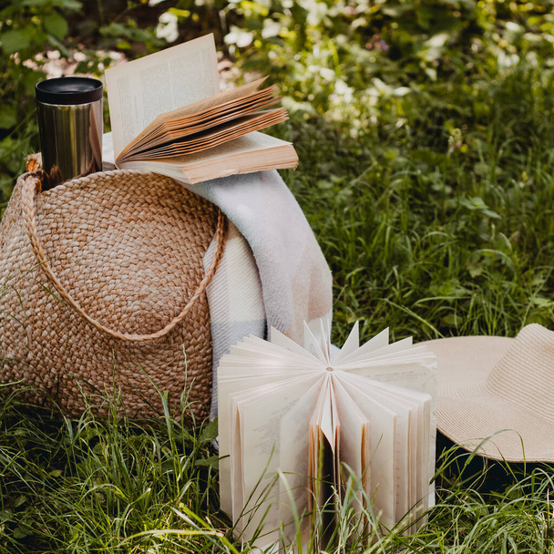 Sac de paille, livre, chapeau et tasse thermo par une journée ensoleillée d'été
 - Photo, image