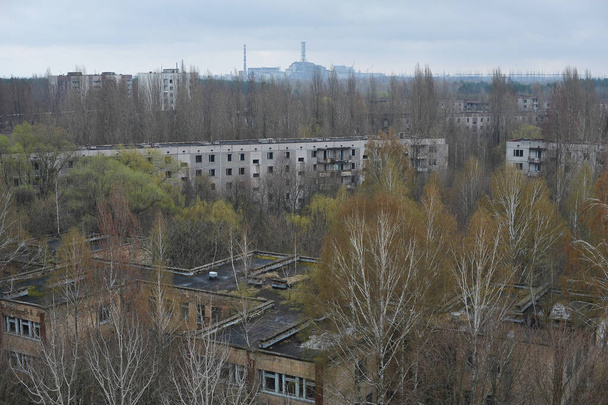 Jardín de infancia y casas en la ciudad fantasma abandonada Pripyat, vista de la planta de energía nuclear, ciudad post apocalíptica, temporada de primavera en la zona de exclusión de Chernobyl, Ucrania
 - Foto, imagen