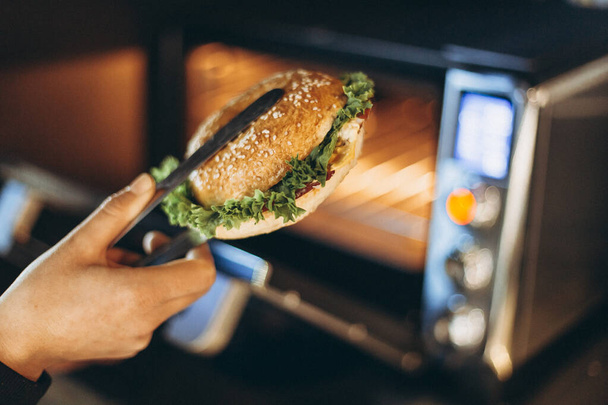ファーストフードのカフェで電子レンジでサンドイッチを作る過程や - 写真・画像