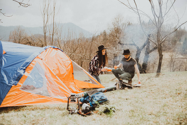 stylish young couple of travelers. Family on a walk in the mountains laid out a tent, prepare breakfast and plan a further itinerary - Fotó, kép