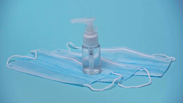 oříznutý pohled na lékaře dávat dezinfekci láhev na lékařské masky na modré - Záběry, video