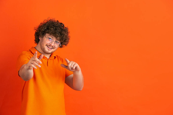 Caucasian young mans monochrome portrait on orange studio background - Fotoğraf, Görsel
