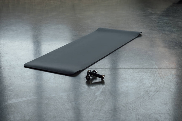 Фітнес килимок з гантелями на підлозі в спортивному центрі
 - Фото, зображення