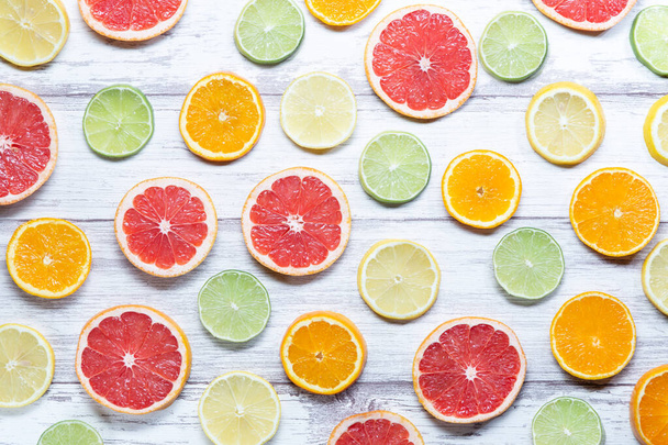 カラフルな果物の背景。柑橘類のスライス、オレンジ、レモン、ライム、グレープフルーツ。白い木の背景。トップ表示. - 写真・画像
