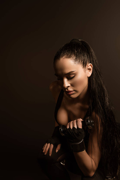 Brünette Sportlerin trainiert mit Kurzhantel isoliert auf schwarz - Foto, Bild